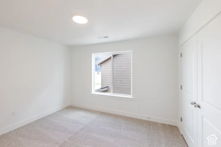 Recessed ceiling light, white walls, carpeted flooring, window with white trim, and white bi-fold doors