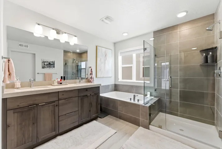 Contemporary bathroom featuring a spacious walk-in shower with glass enclosure, separate soaking tub, dual vanity with undermount sinks, and a large mirror with integrated lighting