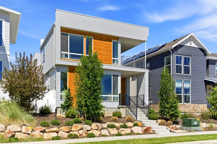 Modern exterior featuring a flat roofline, horizontal wood-finish siding, and a second-story balcony with metal railings