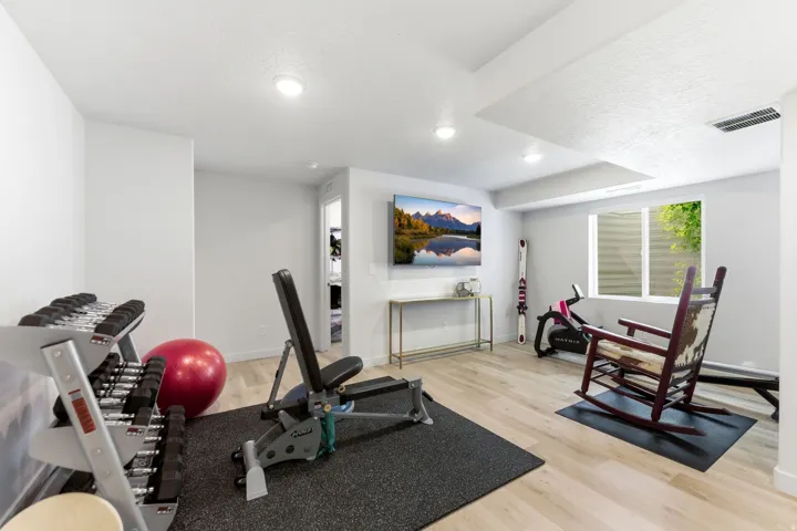 Versatile finished basement space with recessed lighting, light wood-finish flooring, and a large egress window