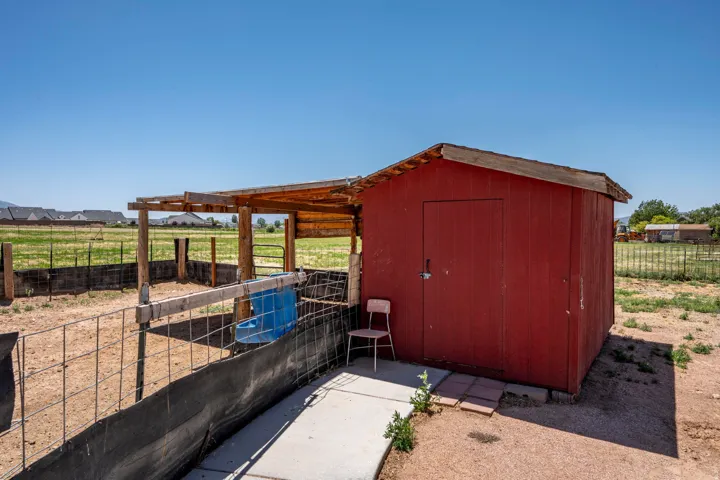 Red-painted shed with a shingled roof and an attached wood-frame lean-to structure