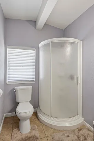 Full bathroom featuring a corner shower enclosure, white toilet, and tile flooring