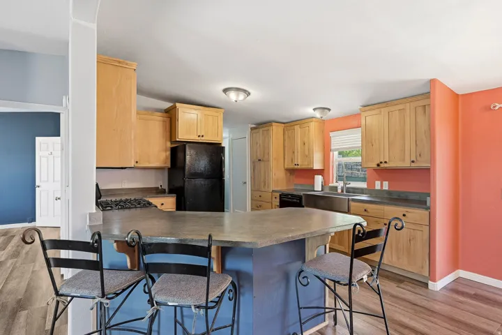 Kitchen featuring light wood-finish cabinetry, a central island with a breakfast bar, and wood-finish flooring