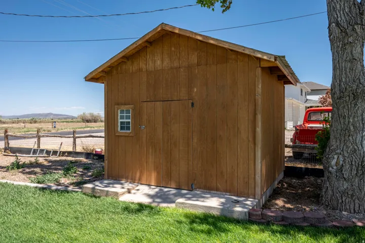Wood-sided shed with a single window and full-height door, set on a concrete foundation
