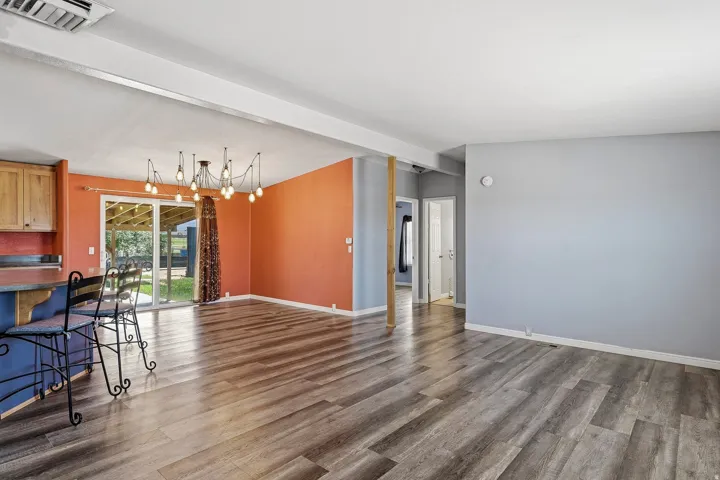 Open-concept living area featuring wood-finish flooring, a modern multi-bulb chandelier, and sliding glass doors to the exterior