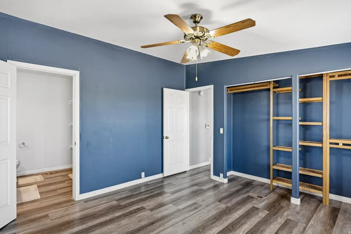Room with wood-finish flooring, a ceiling fan, and blue painted walls