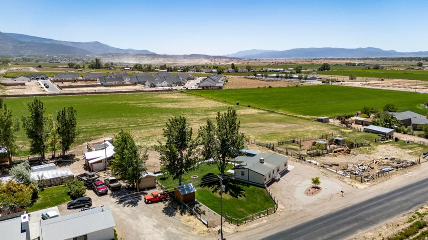 Expansive rural property featuring a main residence, multiple outbuildings, and a large fenced paddock area