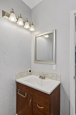 Vanity featuring a wood-finish cabinet with a white countertop and integrated sink
