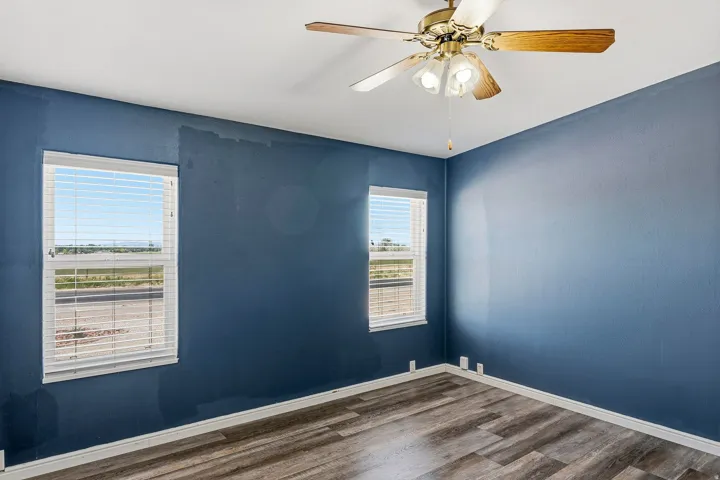 Interior room featuring wood-finish flooring, white baseboards, and two windows with white blinds