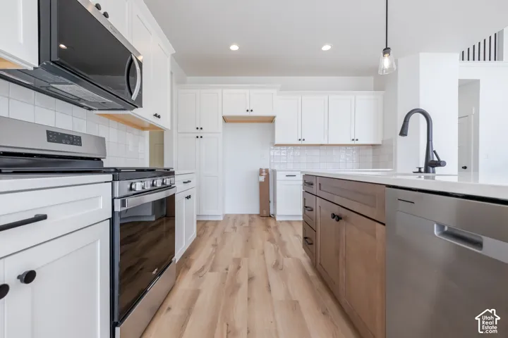 White shaker cabinetry complemented by a wood-finish island, stainless steel appliances, and wood-finish flooring