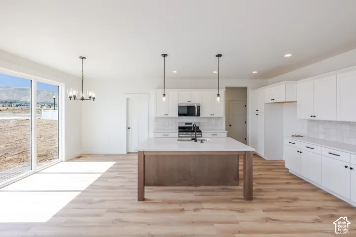Kitchen featuring white cabinetry, subway tile backsplash, stainless steel appliances, and a wood-finish island with a light-toned countertop