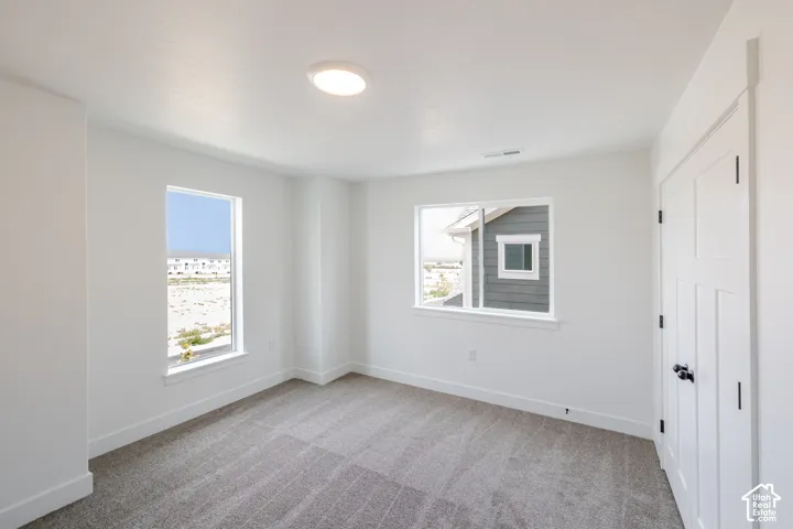Recessed lighting, two large windows, white walls, and gray carpet