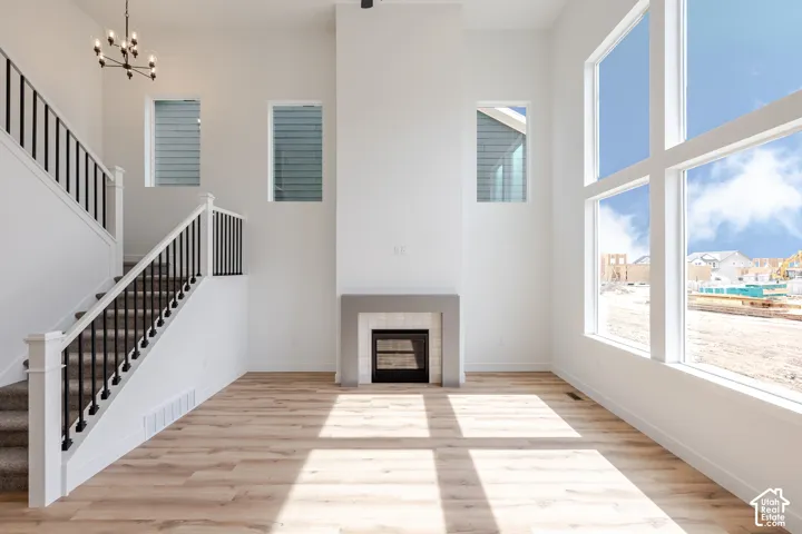 Two-story living area featuring a fireplace with a stone surround, large windows, wood-finish flooring, and a staircase with wrought iron balusters