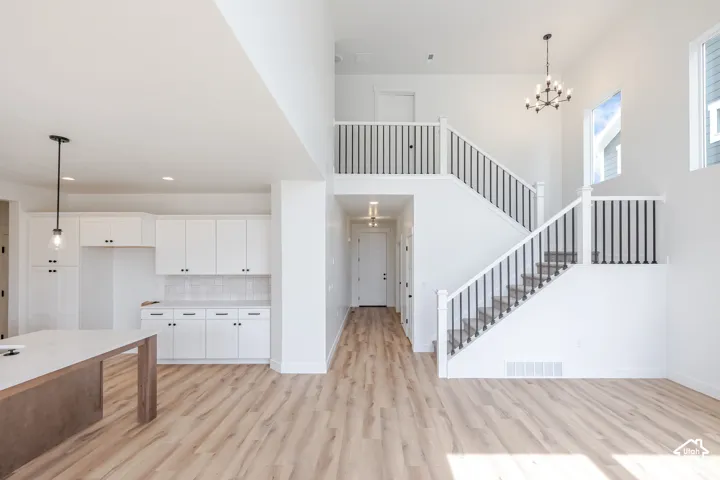 Two-story great room with vaulted ceilings, wood-finish flooring, and a contemporary chandelier