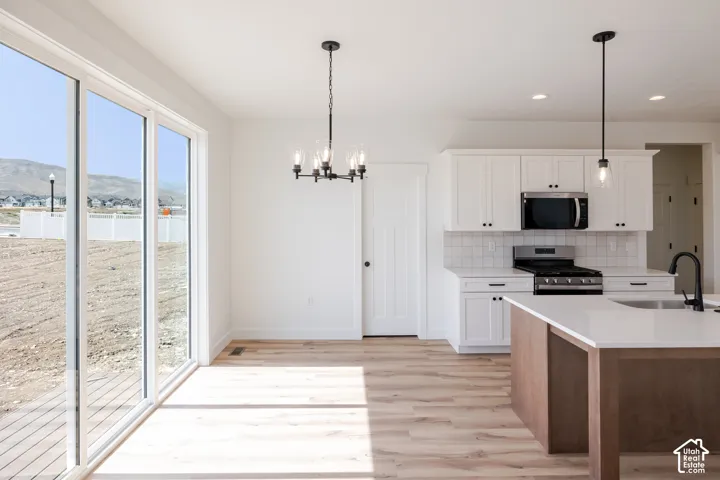 White shaker cabinetry and a tile backsplash complement the stainless steel appliances