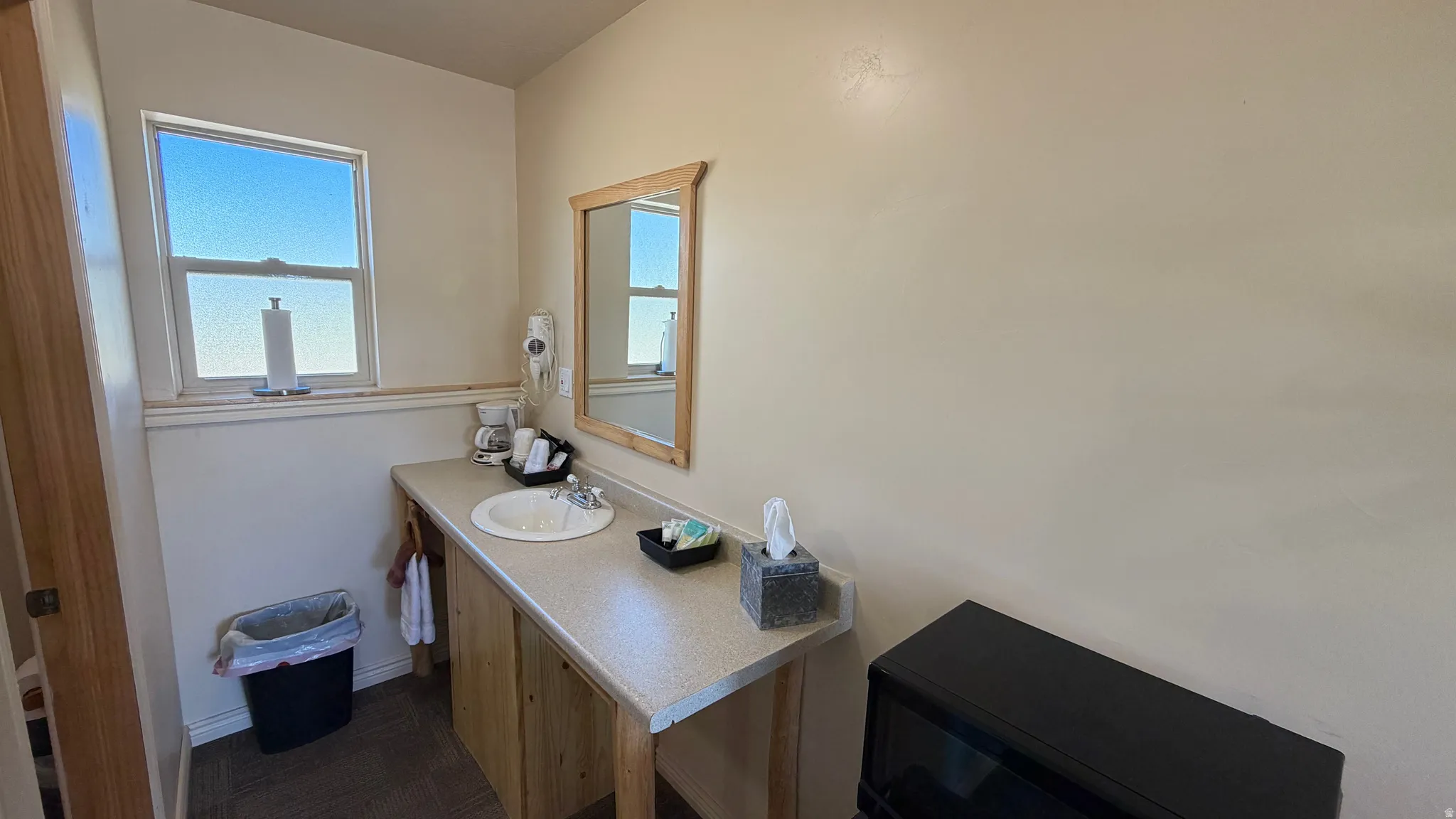 Single vanity with a laminate countertop and an integrated sink, featuring a window and a framed mirror