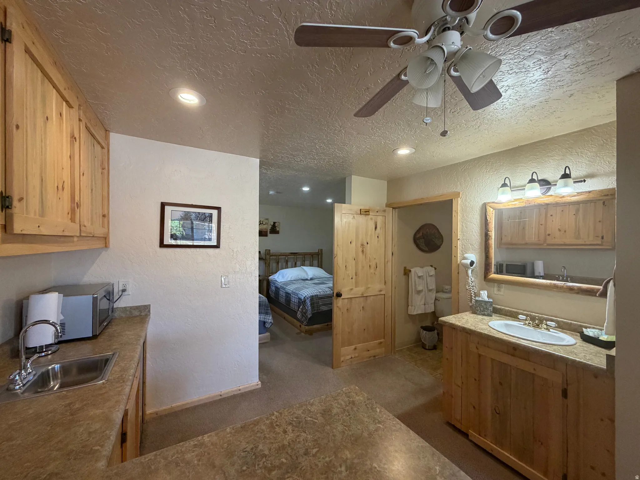 Kitchenette featuring wood cabinetry, laminate countertops, and a stainless steel sink with a chrome faucet