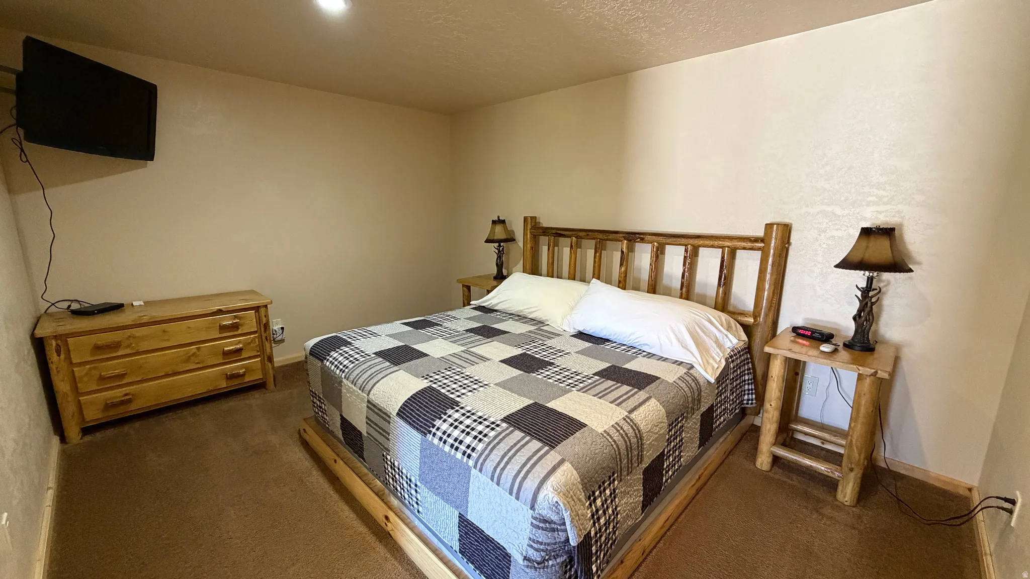 Wood-finish bed frame with matching headboard, neutral wall color, and recessed ceiling lighting