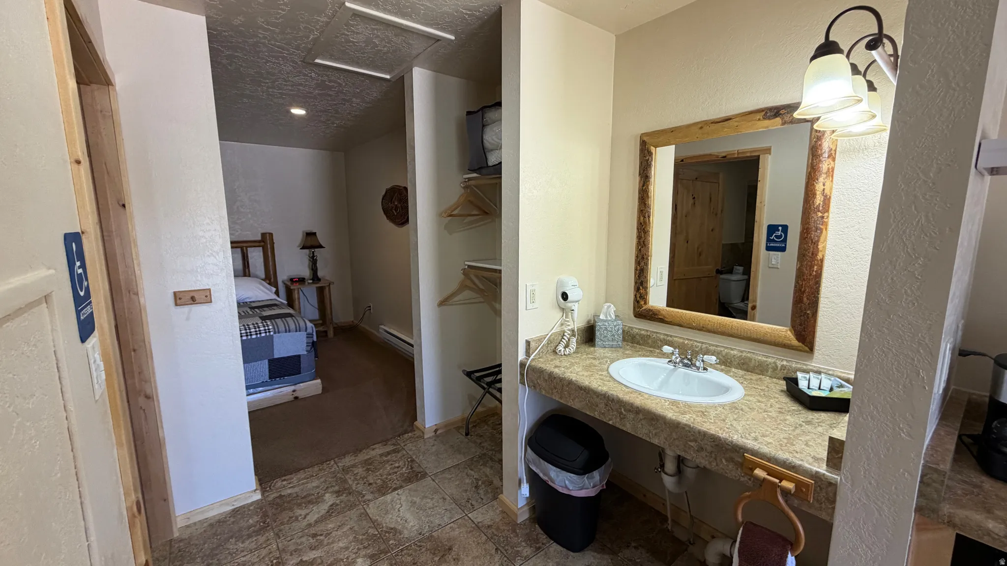 Bathroom vanity featuring a single basin sink, laminate countertop, and wood-framed mirror