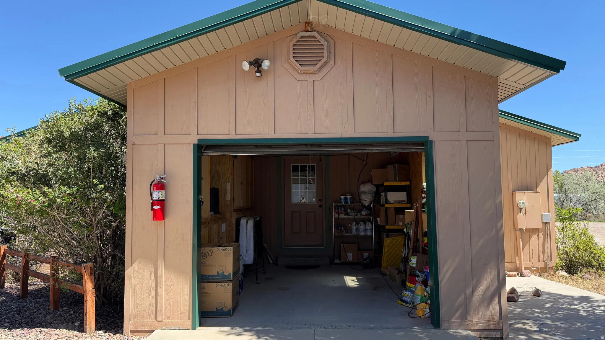 Detached garage structure featuring a roll-up door, horizontal siding, and a green trim roofline
