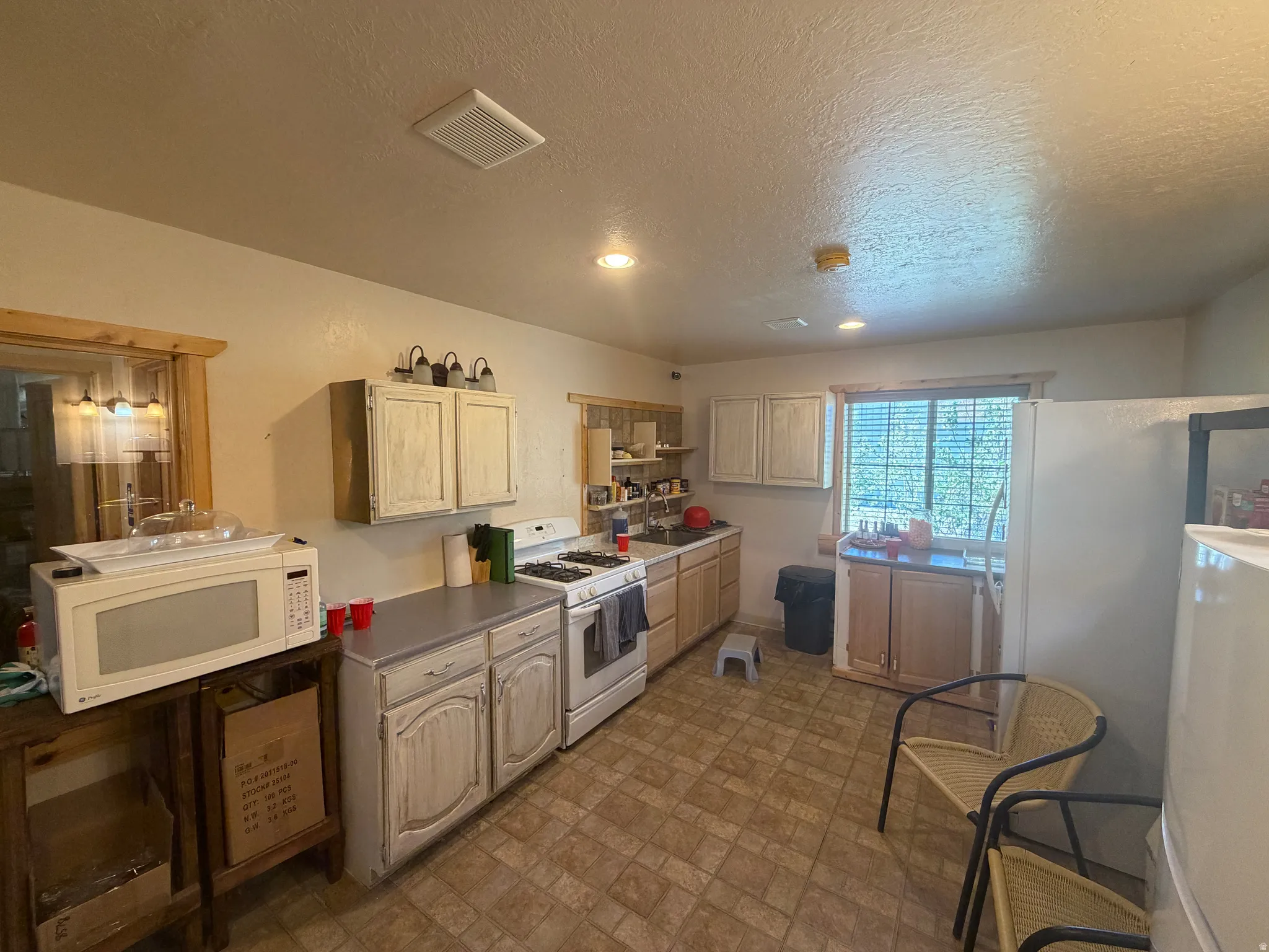 Kitchen featuring a gas range, white cabinetry, and textured ceiling