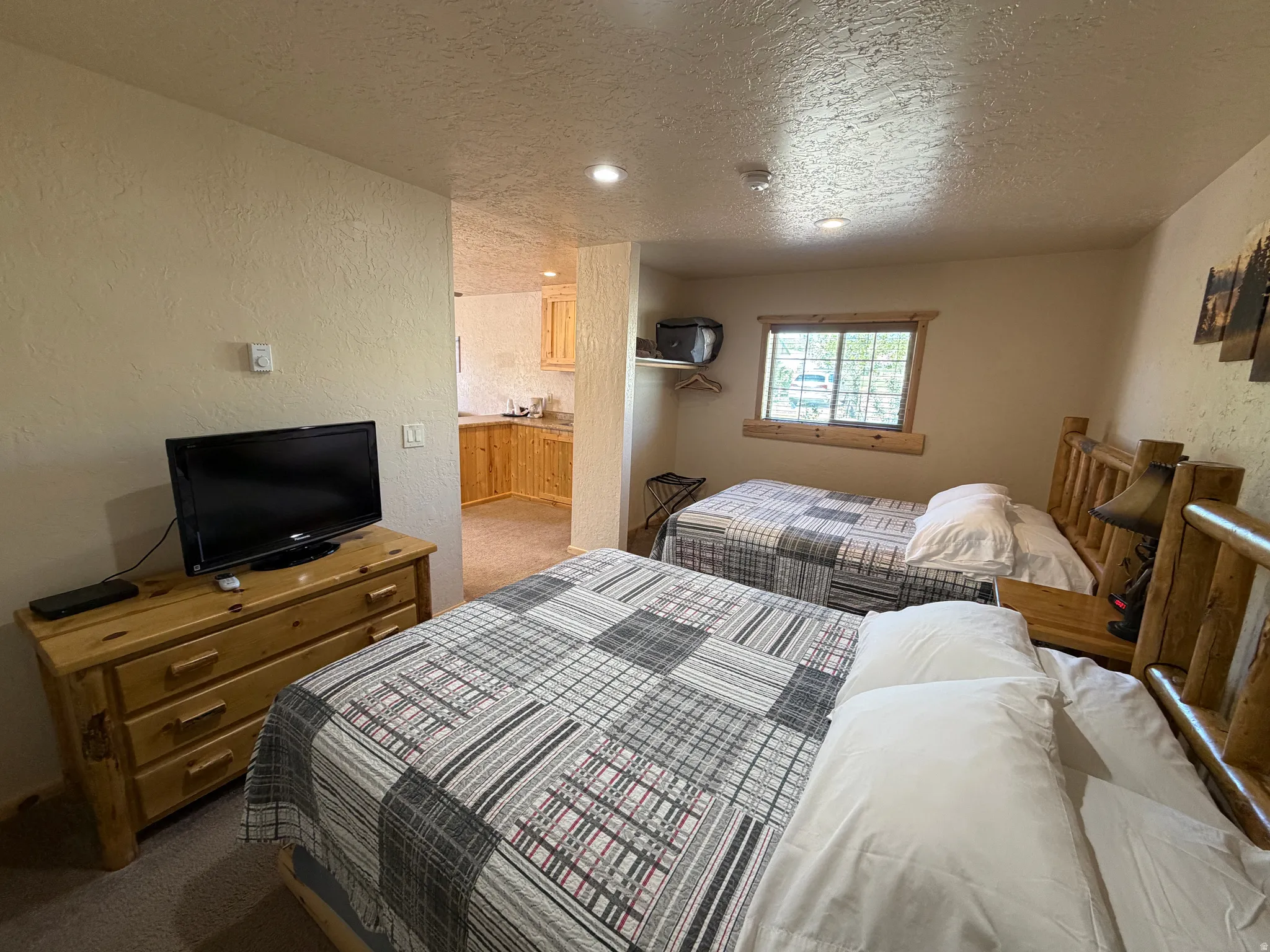 Interior space featuring two wood-frame beds, wood-finish dresser, recessed lighting, and a window with wood trim