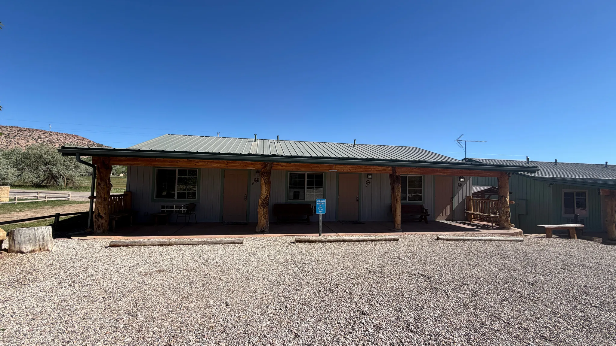 Property exterior featuring a gravel parking area, an extended covered porch with log supports, a metal roof, and a visible mountain backdrop
