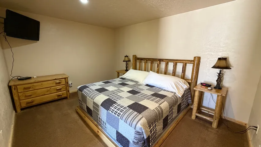 Wood-finish bed frame with matching headboard, neutral wall color, and recessed ceiling lighting