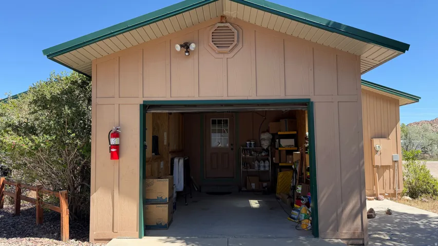 Detached garage structure featuring a roll-up door, horizontal siding, and a green trim roofline