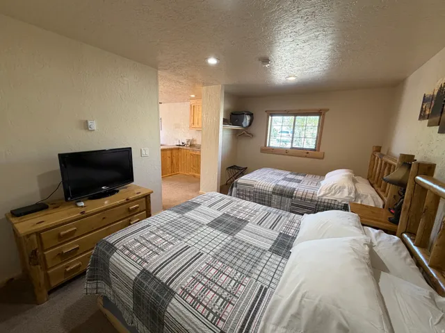 Interior space featuring two wood-frame beds, wood-finish dresser, recessed lighting, and a window with wood trim