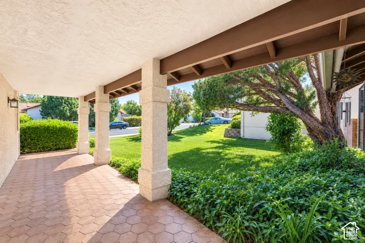 Covered front porch featuring decorative concrete, stucco columns, and exposed wood beams