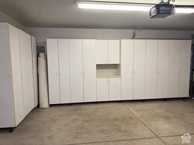 Painted garage and storage system featuring white cabinetry, extra carpet, paint & flooring