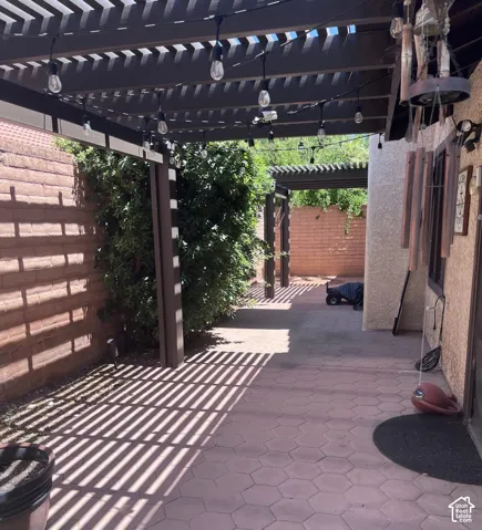 Expansive patio featuring two pergolas with string lighting, and mature perimeter landscaping