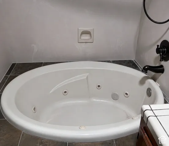 Oval jetted bathtub set into tile, featuring a dark bronze faucet.