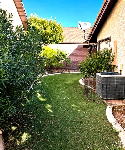 Maintenance-free turf, curved concrete edging, surrounded by mature landscaping and a textured privacy wall