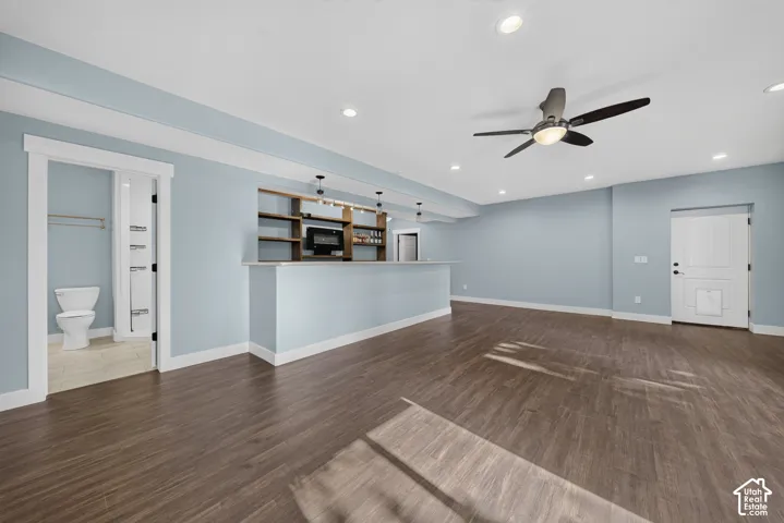 Open-concept living space featuring warm wood-finish flooring throughout, light blue walls, and recessed ceiling lighting