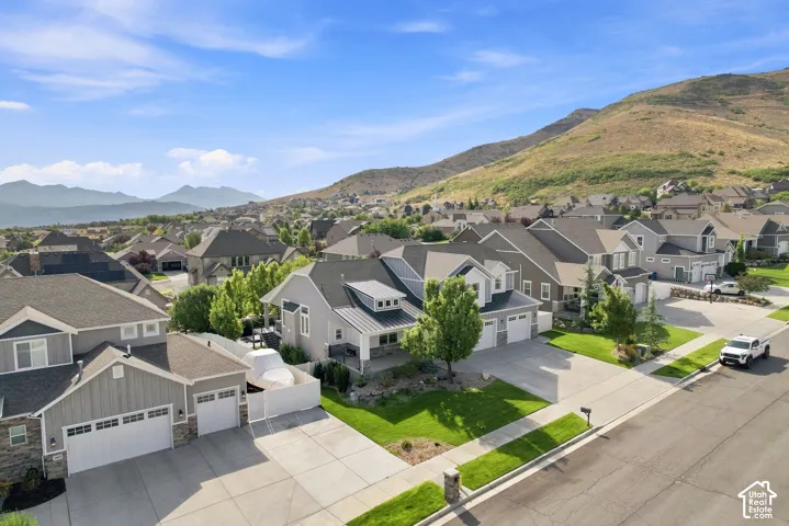 Established residential community nestled against rolling hillside backdrop, featuring multiple two-story homes with varied architectural styles, manicured lawns, and mature landscaping throughout the neighborhood