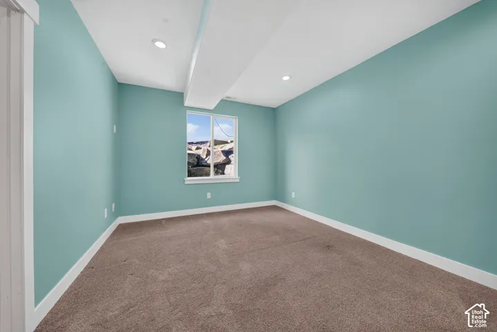 Bright bedroom showcasing soft turquoise walls, white crown molding, and neutral carpet flooring
