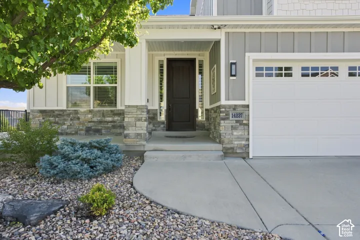 Modern farmhouse front elevation featuring a stone and siding exterior, and professionally landscaped grounds