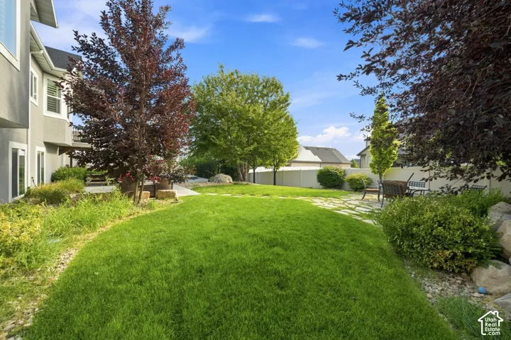 Expansive manicured lawn with mature shade trees, mixed landscaping borders, and established greenery creating a serene outdoor retreat