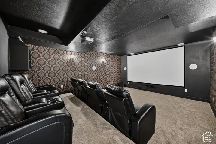 Home Theater featuring a large projection screen, tiered black leather seating with integrated recliners, decorative patterned wallcovering on accent wall, recessed ceiling lighting, and finished flooring throughout