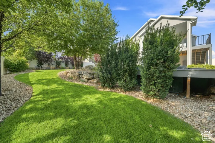 Expansive backyard featuring a manicured lawn, mature landscaping with evergreen plantings, and gravel hardscaping