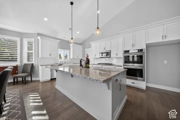 Spacious kitchen with white cabinetry, granite countertops, stainless steel appliances, and wood-finish flooring