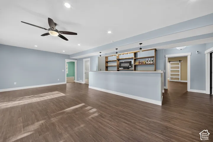 Spacious open-concept room featuring wood-finish flooring, a ceiling fan, recessed lighting, and a built-in bar with open shelving