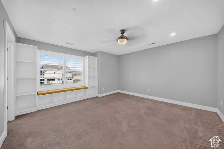 Spacious bedroom with neutral gray walls, plush carpeting, and abundant natural light from large windows