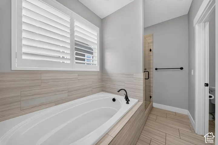 Spa-inspired primary bathroom featuring a soaking tub with matte black fixtures, a walk-in shower with frameless glass enclosure