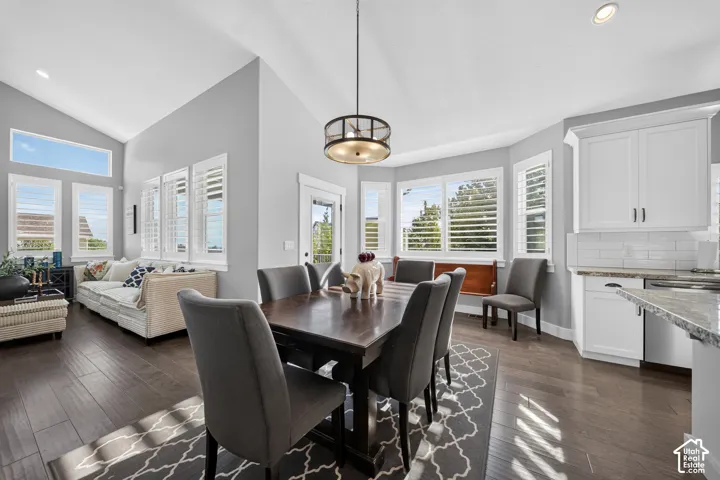 Open-concept living showcasing dark wood-finish flooring, and abundant natural light from multiple windows with operable shutters