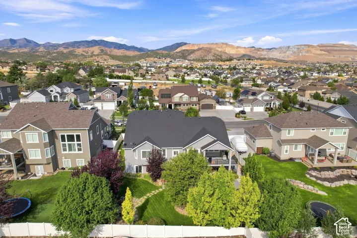 Elevated aerial view showcasing a meticulously landscaped lot with mature evergreen trees, manicured lawn, and multiple residences featuring architectural diversity