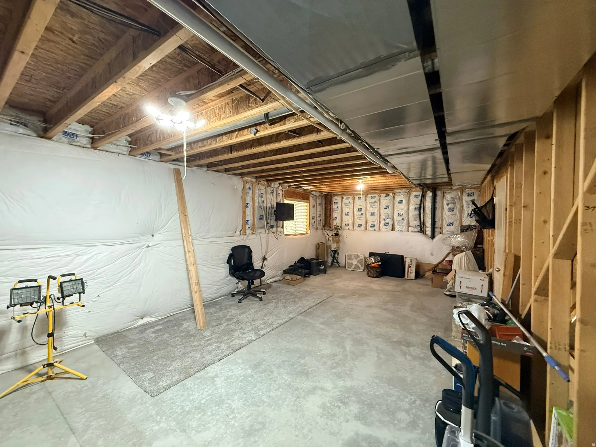 Unfinished basement space featuring exposed wood joists and concrete flooring