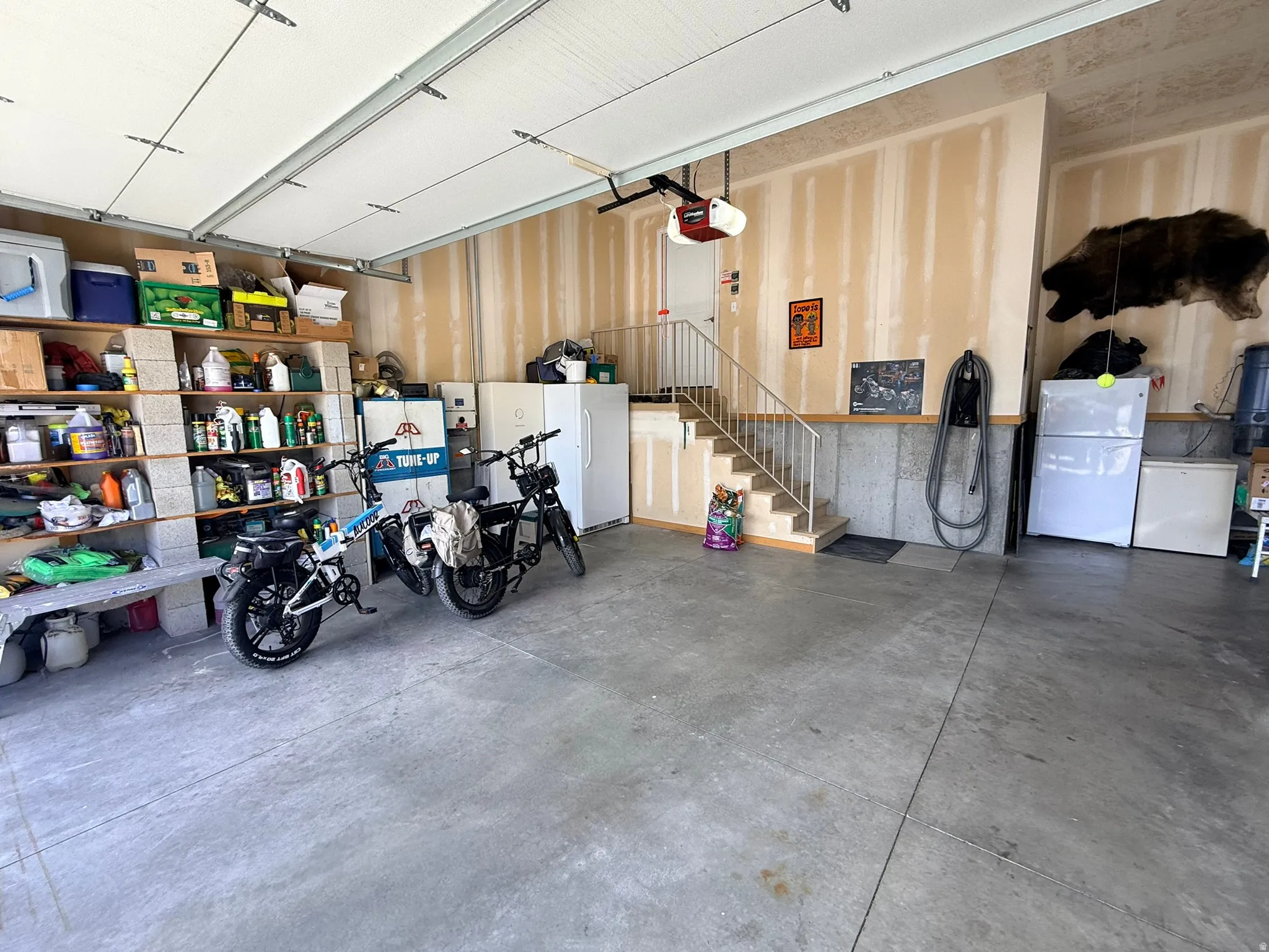 Concrete flooring garage featuring a built-in staircase with metal railings, an overhead garage door, and unfinished walls